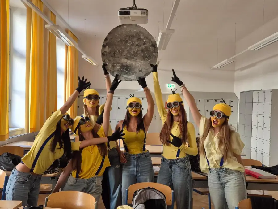 The Minion group in a classroom, lifting the painted moon overhead